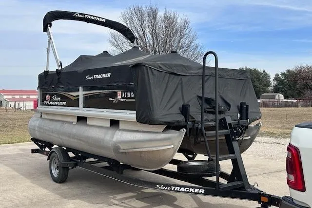 Slide: The Image of 2020 Sun Tracker Bass Buggy 16 DLX pontoon boat on trailer, covered and parked outdoors. - 25