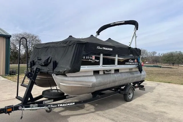 Slide: The Image of 2020 Sun Tracker Bass Buggy 16 DLX pontoon boat on trailer, covered and parked outdoors. - 26
