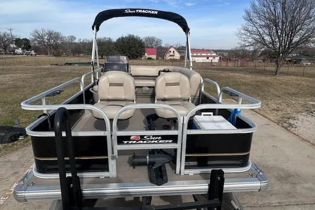 Slide: The Image of 2020 Sun Tracker Bass Buggy 16 DLX pontoon boat on trailer, parked outdoors. - 4