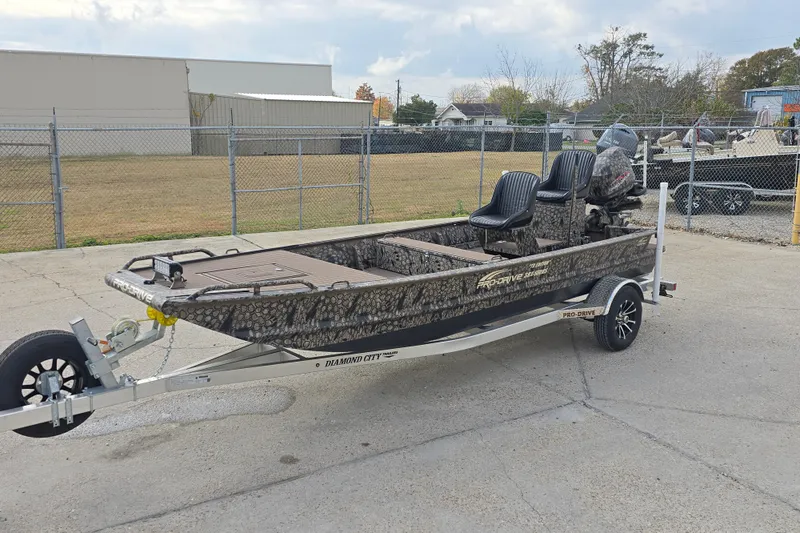 Slide: The Image of 2026 Pro-Drive 1854 SBX TD boat on trailer, camo design, parked outdoors. - 2