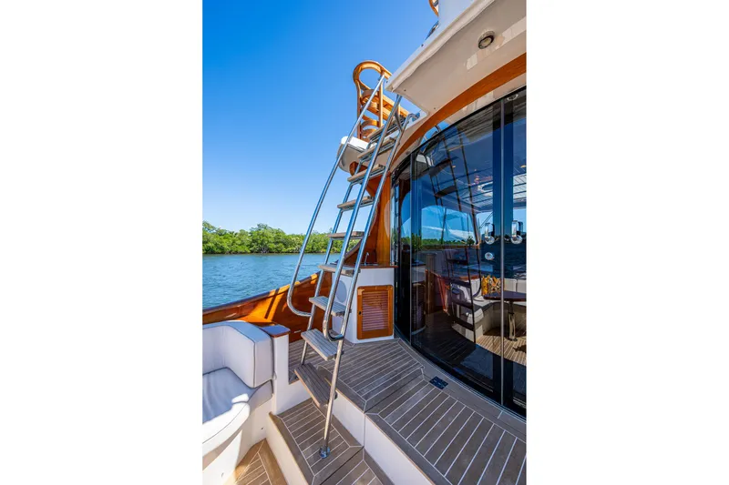 Slide: The Image of 2021 Hinckley Talaria yacht deck with ladder, glass doors, and scenic water view. - 10