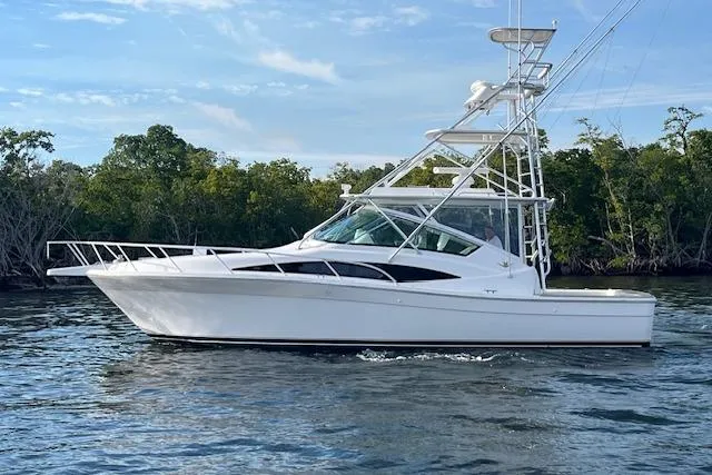 The Image of 2007 Bertram 360 boat on calm water with lush green trees in the background. - 0