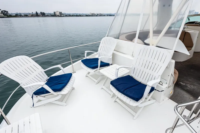 Slide: The Image of 2005 Carver 560 Voyager yacht deck with white chairs and blue cushions. - 23