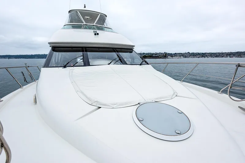 Slide: The Image of 2005 Carver 560 Voyager yacht on calm water, showcasing sleek design and spacious deck. - 8