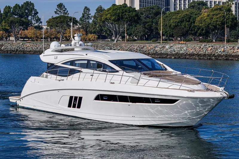 The Image of 2016 Sea Ray L590 yacht cruising on a calm waterway, surrounded by trees and buildings. - 1