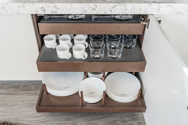 Slide: The Image of Cabinet with organized dishes and glasses in a 2016 Sea Ray L590 yacht kitchen. - 31