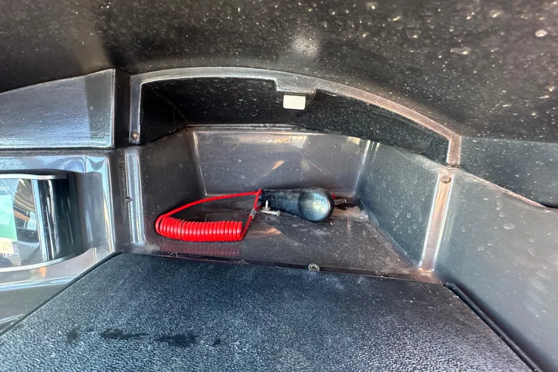 Slide: The Image of 2016 Monterey 218 Surf boat interior compartment with red coiled cable and black plug. - 57