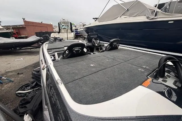 Slide: The Image of 2024 Skeeter FXR21 Limited boat with spacious deck and seating, docked in a marina. - 14