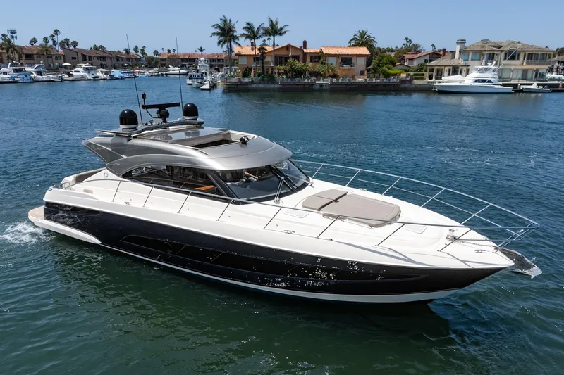 The Image of 2021 Riviera 4800 Sport Yacht cruising in a scenic marina setting. - 0