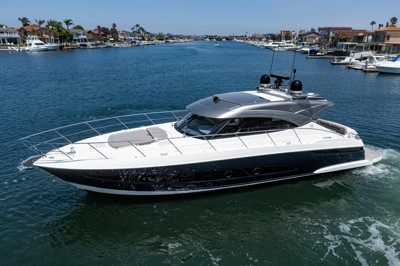 Slide: The Image of 2021 Riviera 4800 Sport Yacht cruising in a scenic waterfront setting. - 1
