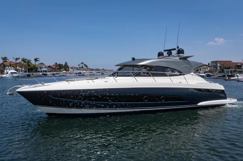 Slide: The Image of 2021 Riviera 4800 Sport Yacht cruising on a sunny day in a marina. - 12