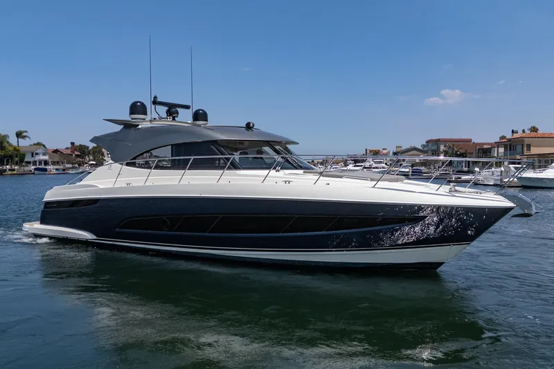 Slide: The Image of 2021 Riviera 4800 Sport Yacht cruising in a marina under a clear blue sky. - 13
