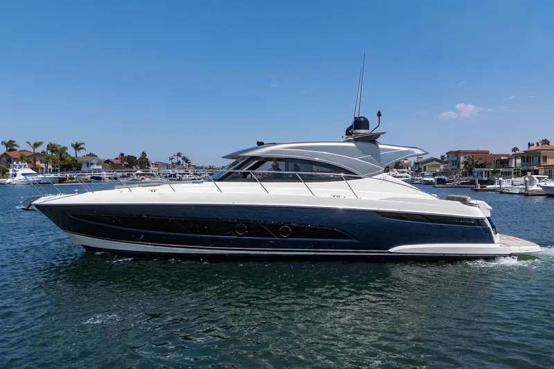 Slide: The Image of 2021 Riviera 4800 Sport Yacht cruising in a sunny marina setting. - 2