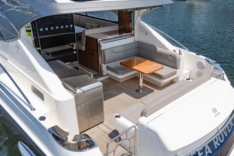 Slide: The Image of 2021 Riviera 4800 Sport Yacht with elegant seating and dining area on the deck. - 22