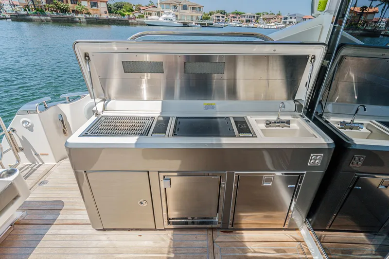 Slide: The Image of Outdoor kitchen on 2021 Riviera 4800 Sport Yacht, featuring grill and sink by the water. - 28