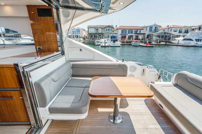 Slide: The Image of 2021 Riviera 4800 Sport Yacht interior with elegant seating and table, overlooking marina. - 30