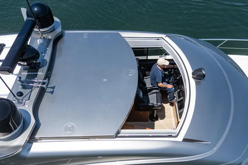Slide: The Image of 2021 Riviera 4800 Sport Yacht with open sunroof, captain at helm, cruising on water. - 45