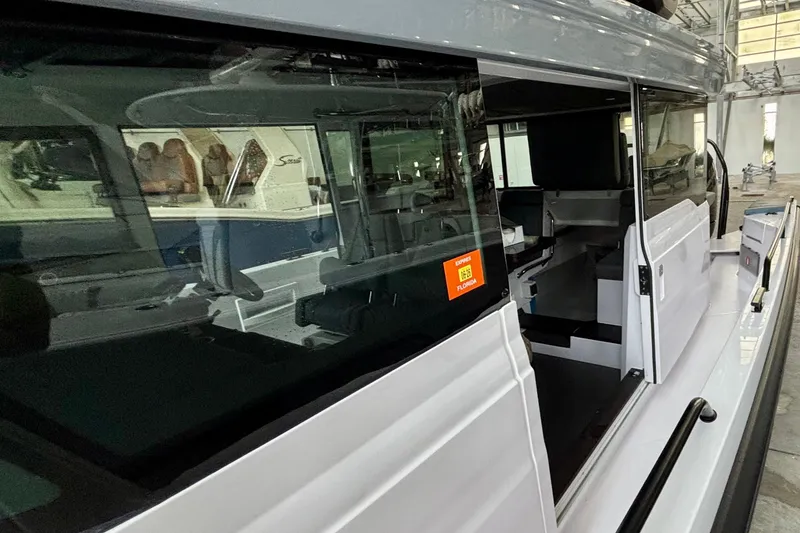 Slide: The Image of 2024 Axopar 37 XC Cross Cabin boat interior with sleek white design in a marina setting. - 26
