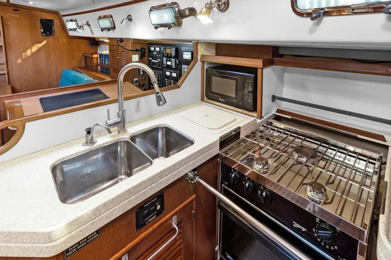 Slide: The Image of 2006 Island Packet 440 yacht kitchen with dual sink, stove, and microwave. - 21