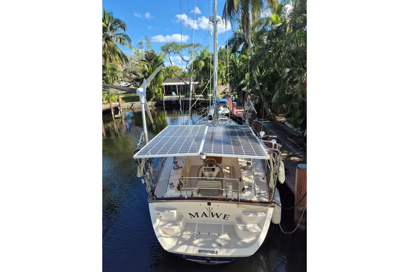 Slide: The Image of 2006 Island Packet 440 sailboat with solar panels docked in a lush, tropical setting. - 6