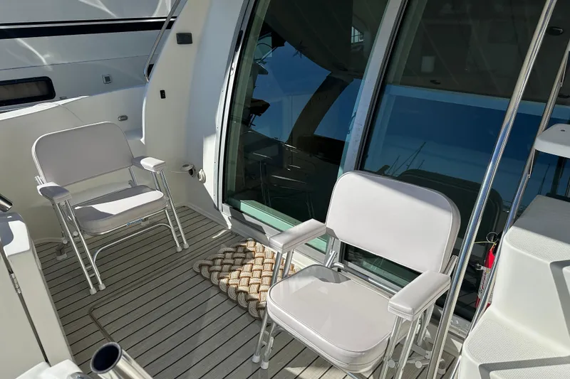 Slide: The Image of 2000 Maxum 4600 SCB yacht deck with two white chairs and glass doors. - 3