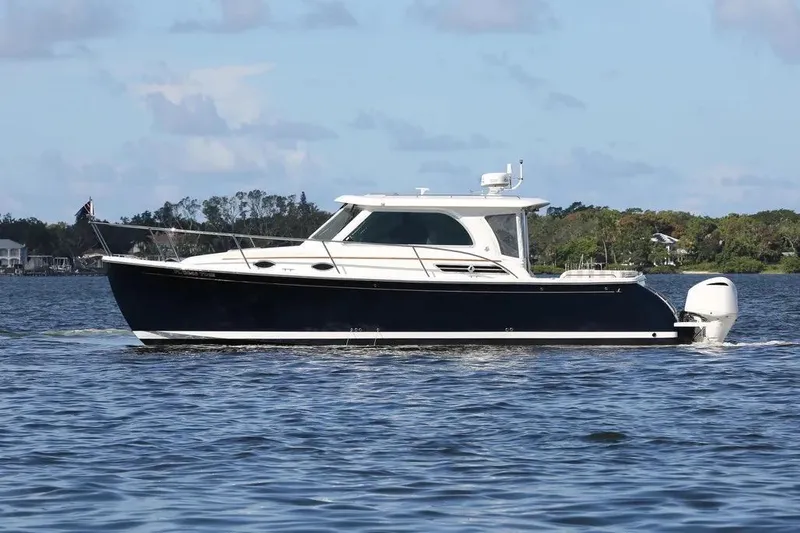 The Image of 2019 Back Cove 34O boat cruising on a calm lake under a clear sky. - 0