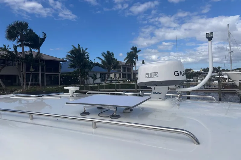 Slide: The Image of 2019 Back Cove 34O boat with Garmin xHD radar, docked near palm trees and houses. - 2