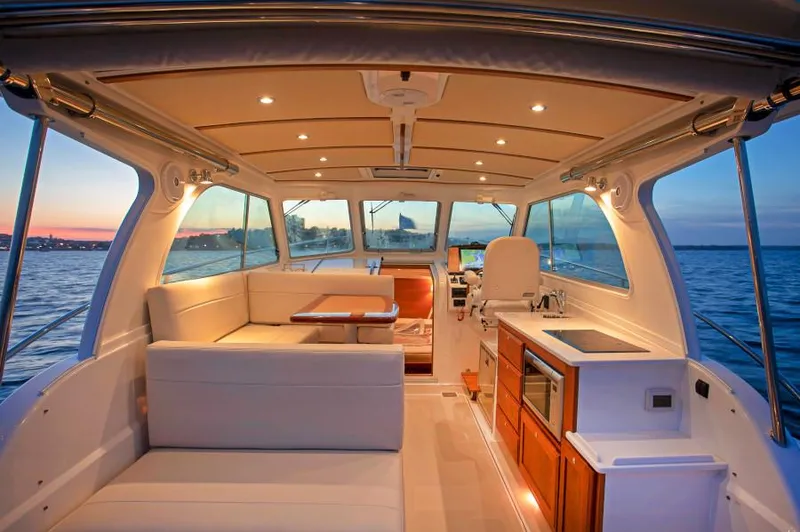 Slide: The Image of Manufacturer Provided Image: 2019 Back Cove 34O yacht interior with sunset view, modern seating, and kitchenette. - 21