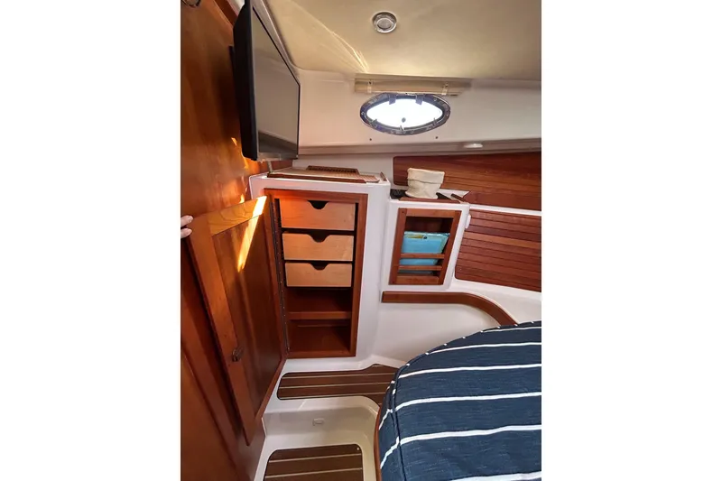 Slide: The Image of Interior of 2019 Back Cove 34O boat with wooden cabinetry and striped bedding. - 26