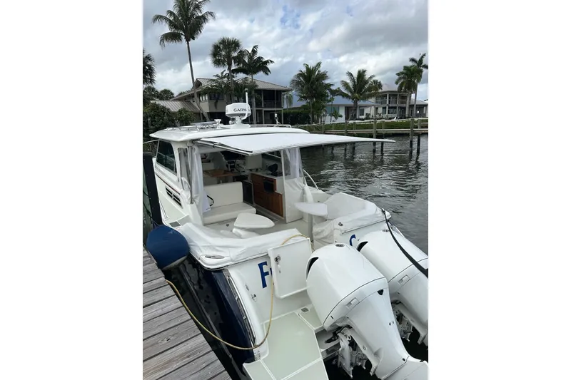 Slide: The Image of 2019 Back Cove 34O boat docked, featuring dual outboard engines and a sleek design. - 5