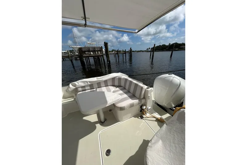 Slide: The Image of 2019 Back Cove 34O boat with striped seating, docked by calm waters. - 7