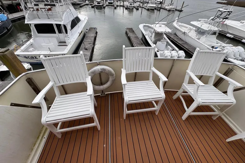 Slide: The Image of Three white chairs on the deck of a 1988 Jefferson 52 Monticello yacht in a marina. - 11