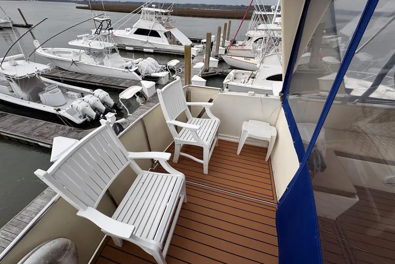 Slide: The Image of 1988 Jefferson 52 Monticello yacht deck with white chairs, overlooking marina with boats. - 13