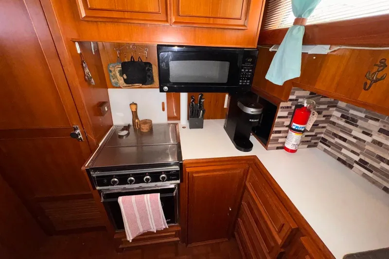 Slide: The Image of Compact kitchen in a 1988 Jefferson 52 Monticello boat with stove, microwave, and fire extinguisher. - 36