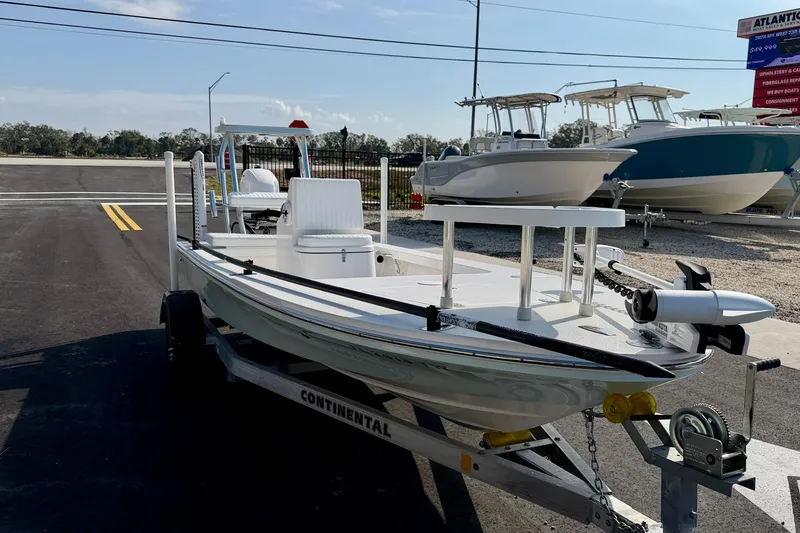 Slide: The Image of 2024 Outlaw Legend 17 boat on trailer, parked outdoors, with other boats in the background. - 2