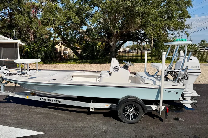 Slide: The Image of 2024 Outlaw Legend 17 boat on trailer, parked outdoors with trees in background. - 3