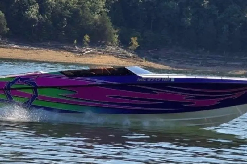 Slide: The Image of 1992 Fountain 27 Fever speedboat with vibrant pink and green design on a lake. - 2