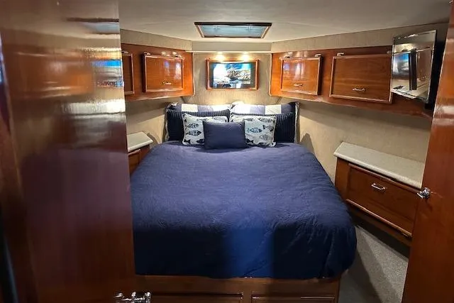 Slide: The Image of 1988 Ocean 44' Super Sport yacht bedroom with wooden cabinets and blue bedding. - 36