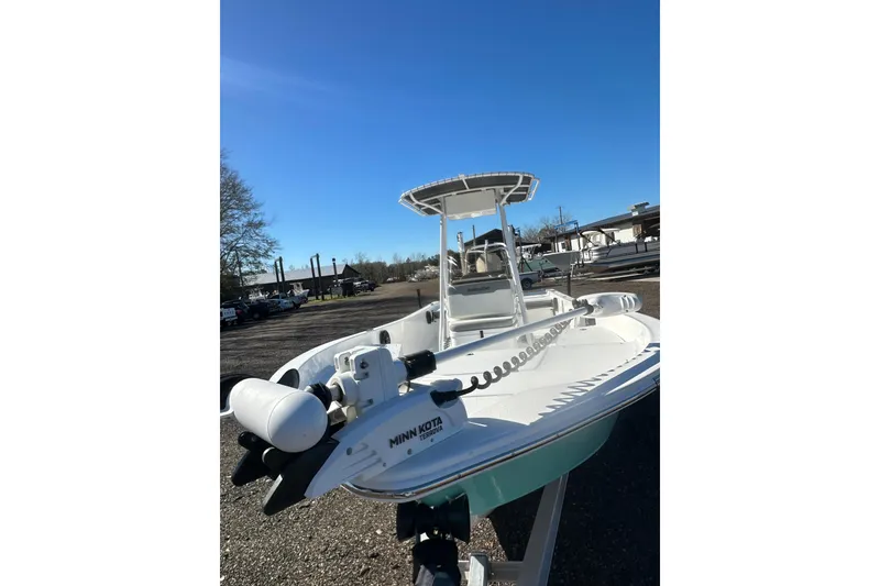 Slide: The Image of 2026 Action Craft 24 Bay boat with Minn Kota trolling motor, parked outdoors. - 12