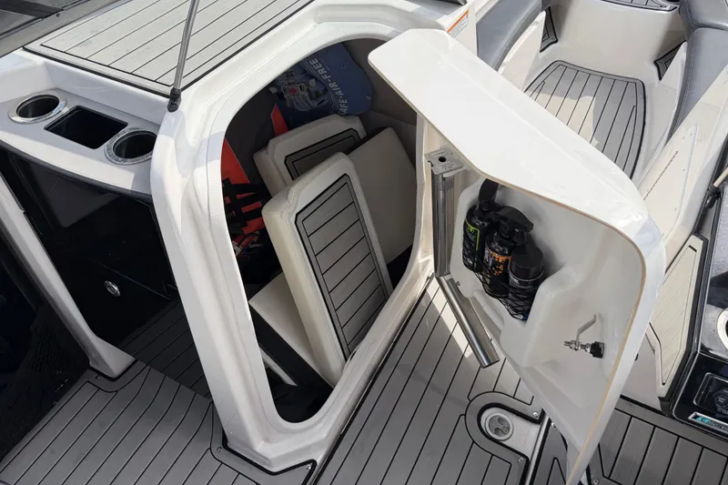 Slide: The Image of 2022 Yamaha Boats 252SD storage compartment with safety gear and cup holders. - 19