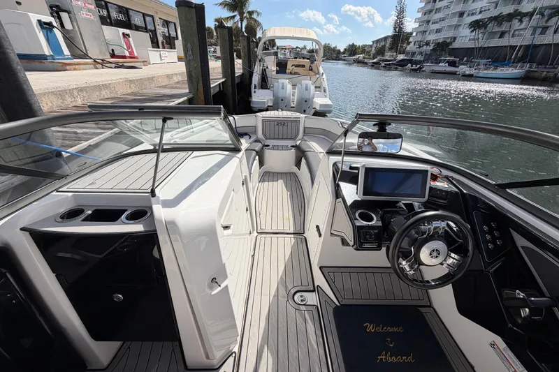 Slide: The Image of 2022 Yamaha Boats 252SD interior, featuring sleek dashboard and modern controls at a marina. - 20