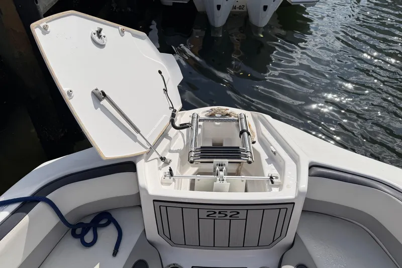 Slide: The Image of 2022 Yamaha Boats 252SD anchor compartment open, docked by water. - 24