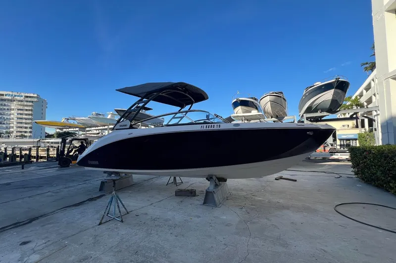 Slide: The Image of 2022 Yamaha Boats 252SD interior with luxurious seating at a marina dock. - 6