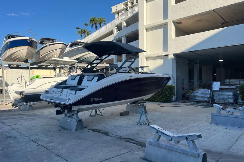 Slide: The Image of 2022 Yamaha Boats 252SD interior with luxurious seating, docked by a serene waterfront. - 7