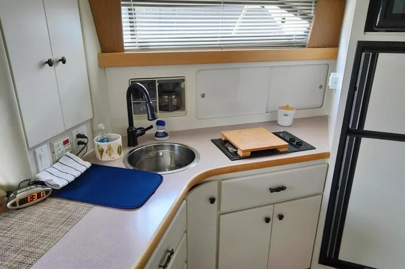 Slide: The Image of 1994 Carver 380 Santego yacht kitchen with sink, stove, and cutting board. - 10