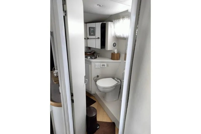 Slide: The Image of 1994 Carver 380 Santego yacht bathroom with toilet, sink, and storage cabinets. - 24