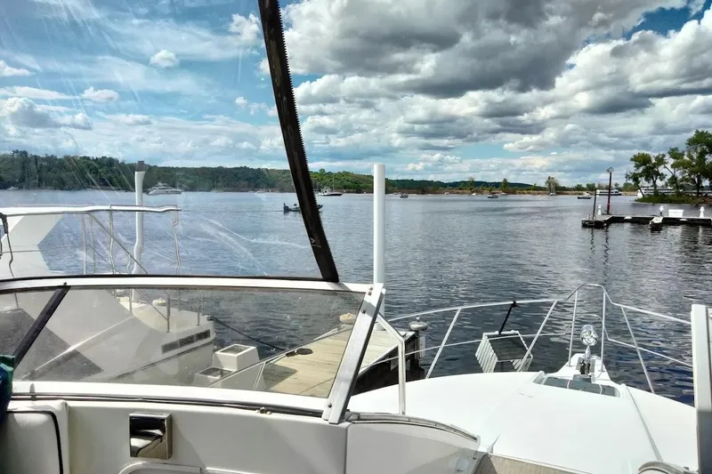 Slide: The Image of 1994 Carver 380 Santego yacht docked on a serene lake under a partly cloudy sky. - 31