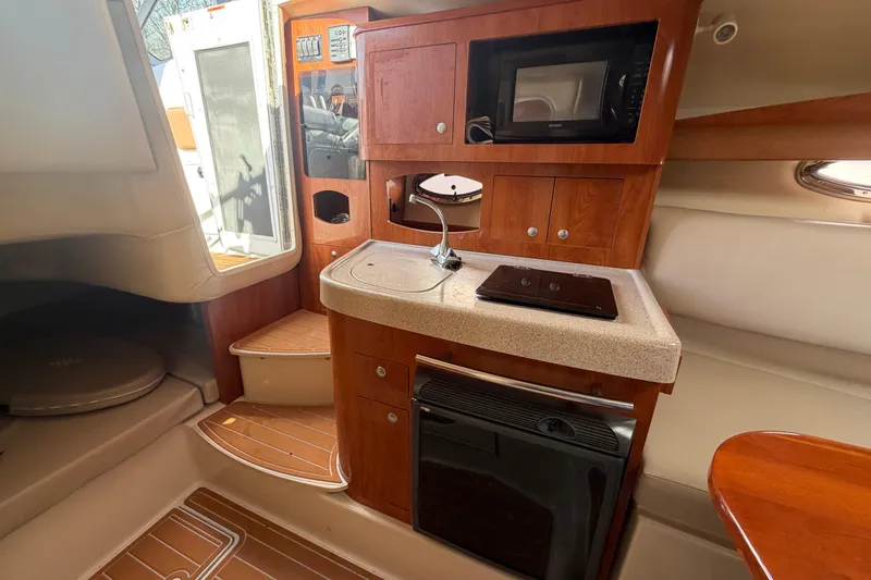 Slide: The Image of 2006 Four Winns 278 Vista boat interior with kitchenette, featuring wood cabinetry and modern appliances. - 21