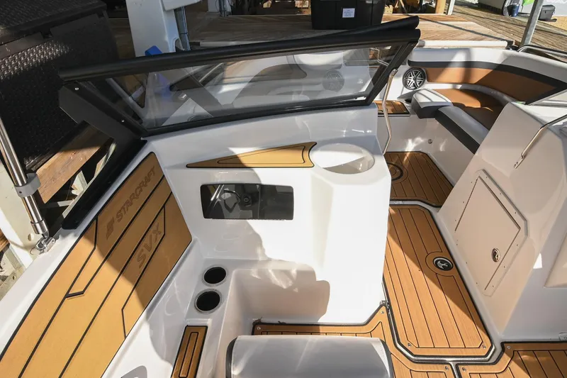 Slide: The Image of 2023 Starcraft SVX 230 IO boat interior with tan and black seating, cup holders, and wood-style flooring. - 20