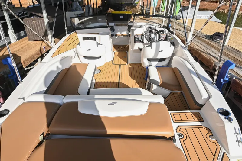 Slide: The Image of 2023 Starcraft SVX 230 IO boat interior with tan and white seating, docked at a marina. - 6